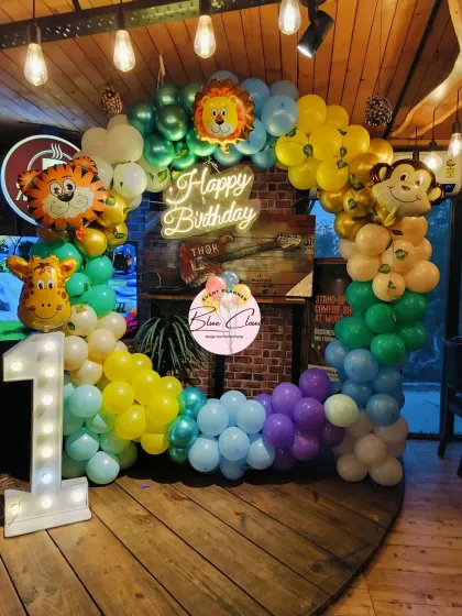 A square balloon arch for a jungle-themed first birthday, featuring a neon sign and large animal foil balloons.