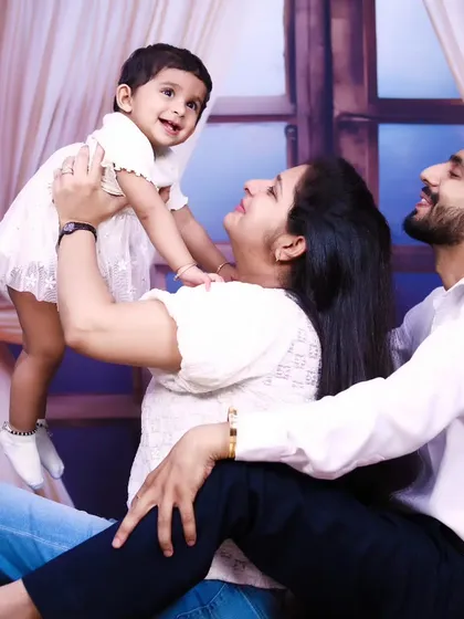 A dynamic and joyful family photo, with the mother lifting her daughter up in the air.