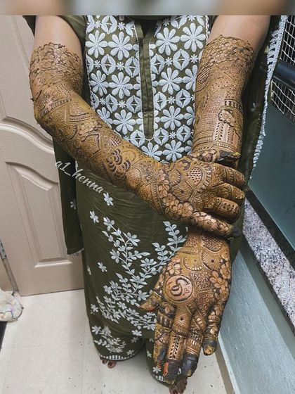 A complete look at bride Daniya's henna, including the custom initial "S" worked into the palm design.
