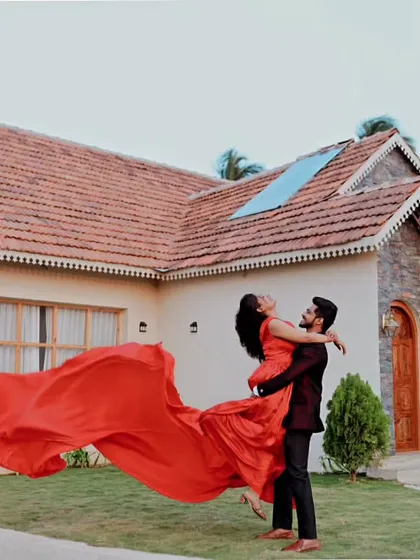 Capturing pure joy with a beautiful lift. This shot highlights the movement and flow of our red trail gown, making it look effortless and romantic against a charming cottage backdrop.