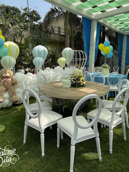 A seating arrangement at the baby shower with a large teddy bear and the hot air balloon display in the background.