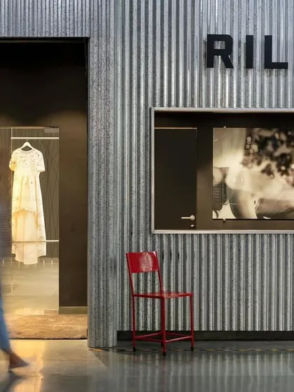 A glimpse of the Rilievi showroom, where a single red chair provides a pop of color against the industrial corrugated metal walls. The space is a testament to bold, contrasting design.