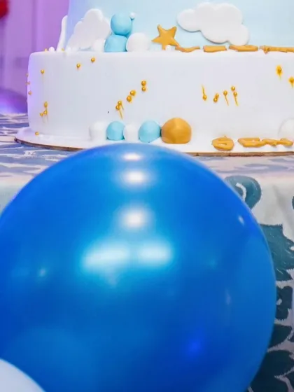 A shot focusing on a bright blue balloon in the foreground with the birthday cake visible behind it, creating a sense of depth and context.