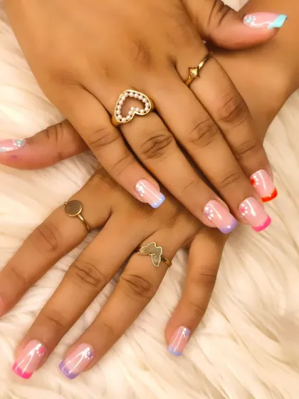 A playful and colorful look with rainbow French tips on each nail, accented with tiny star glitter for extra sparkle.