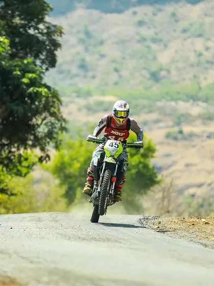 Anish Shetty at speed on his rally bike through a tree-lined section.