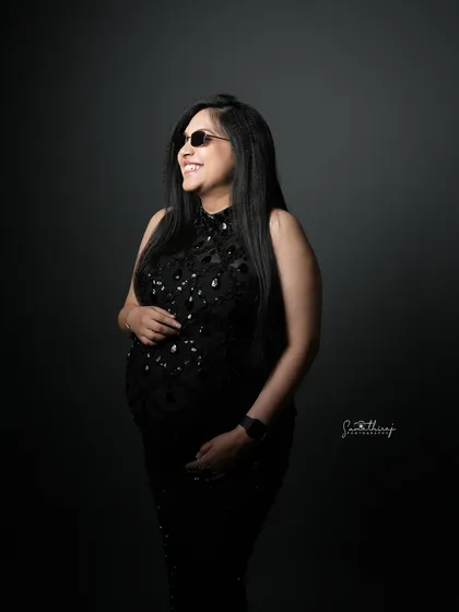A glamorous portrait of a mother-to-be in a black sequined gown and sunglasses. Her confident smile and stylish look create a fun and modern maternity photo.
