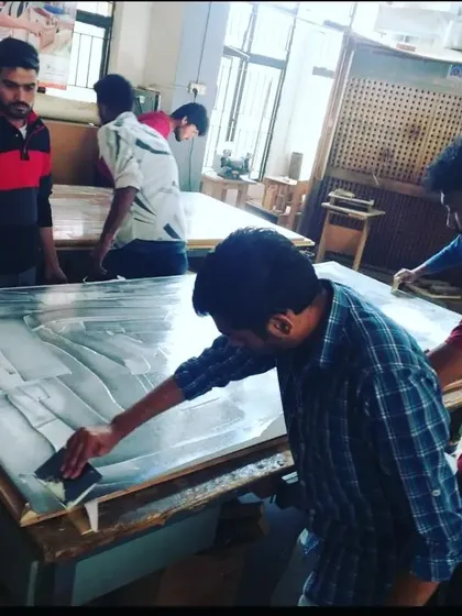 Diploma students prepare plywood and laminates for the hot press machine, a process used in manufacturing modular furniture panels.