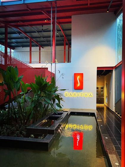 The interior of the Saritha Serene marketing office, where a bold red structure frames an indoor water body and planters. This photo shows our ability to create powerful brand statements by integrating landscape and architecture.