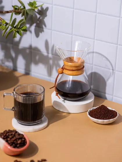A styled product shot of a Chemex brewer. The clean, bright lighting and simple props create a modern and minimalist aesthetic.