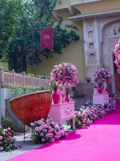 The welcome aisle was a vision in pink. We lined the path with oversized floral arrangements in modern vases, antique-style drawers, and a custom mirror sign to greet guests with elegance and charm.