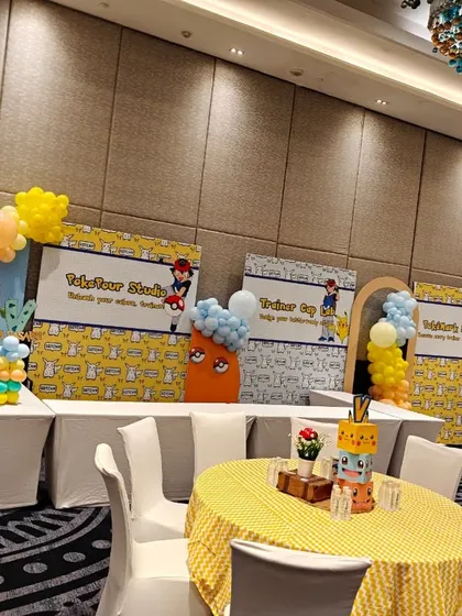 A full view of a themed banquet hall setup, showing the stage, table arrangements, and balloon decor that create a cohesive party environment.