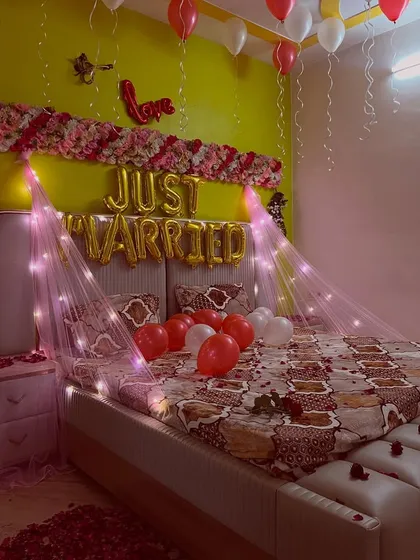 A close-up of the bed decoration, with red and white balloons and a 'Love' foil balloon accent.