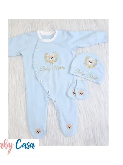 A closer look at the matching romper, cap, and mittens for the "Baby Mehta" set. The light blue fabric is embroidered with a golden lion crest for a touch of elegance.