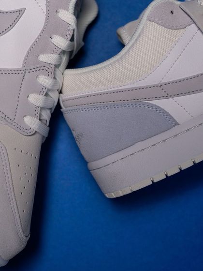 A close-up showing the material interplay on the Jordan 1 Low 'Paris', with smooth leather, textured suede, and woven textiles.