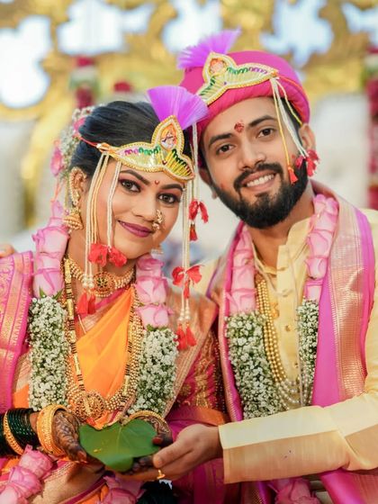A classic portrait of a Maharashtrian couple during their wedding ceremony. Their coordinated pink and yellow outfits and happy smiles make for a picture-perfect memory.