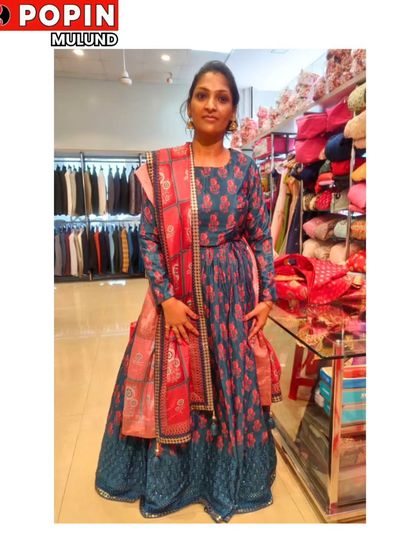 A happy client trying on a beautiful blue and pink Anarkali-style gown in my store. Her smile is the best review.