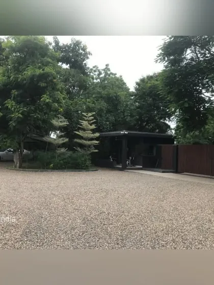 The gravel driveway provides ample space for vehicles while maintaining a soft, natural aesthetic that complements the surrounding trees and the modern architecture of the home.
