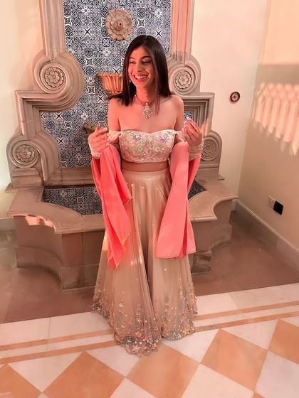 This is the final look of the light gold lehenga featuring the colorful floral embroidery. Paired with an off-shoulder blouse and detachable velvet sleeves, it’s a perfect example of how detailed handwork creates a truly unique outfit.