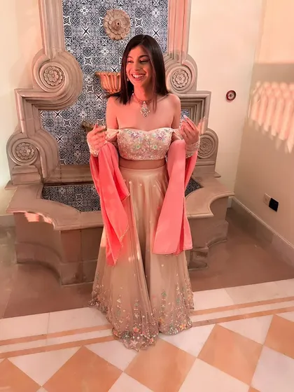 This is the final look of the light gold lehenga featuring the colorful floral embroidery. Paired with an off-shoulder blouse and detachable velvet sleeves, it’s a perfect example of how detailed handwork creates a truly unique outfit.