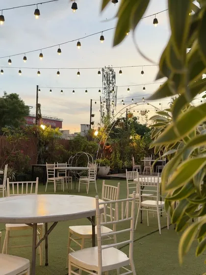 A daytime view of the Terrace Garden, with simple table settings under strings of lights, ready for an afternoon gathering.