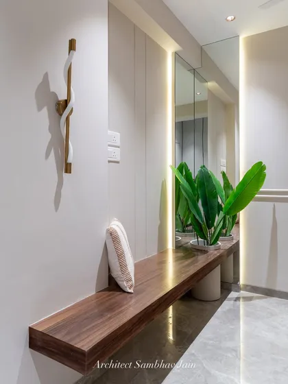 A serene corner designed to unwind. This wooden veneer shelf doubles as a seat or daybed, seamlessly extending into a tall, inbuilt planter box. The L-shaped mirror reflects the lush greens and expands the visual depth of the space.