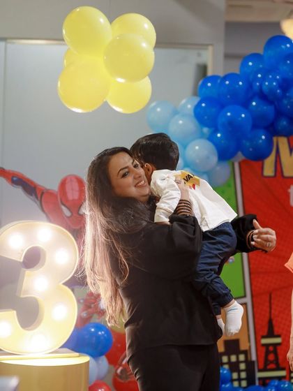 A tender moment between mother and son, with the glowing number '3' and a superhero backdrop setting a magical scene. We help create the perfect atmosphere for these cherished family memories.
