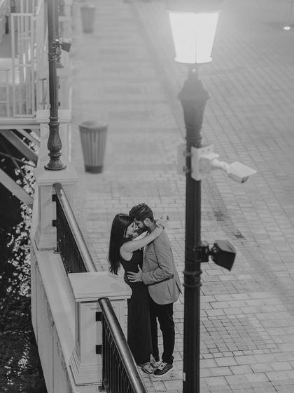 A romantic embrace under a streetlamp. This black and white photo has a classic, cinematic quality, capturing a quiet, intimate moment away from the crowd during their destination pre-wedding shoot.