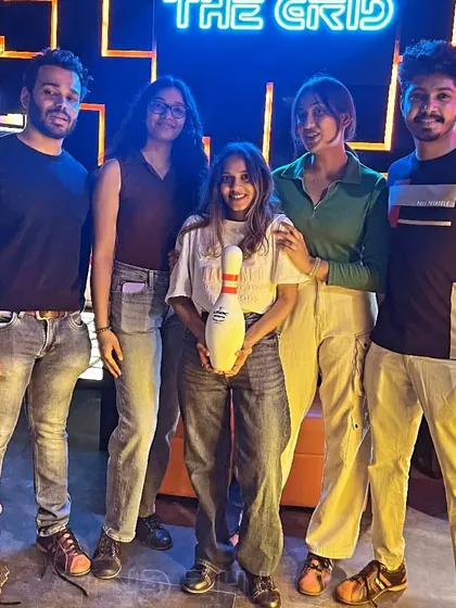 A group of friends posing with a bowling pin. Not sure what's more impressive, their scores or their poses.