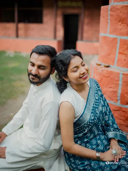 A peaceful and serene moment. The couple sits back-to-back with their eyes closed, soaking in the quiet happiness of being together during their traditional pre-wedding shoot.
