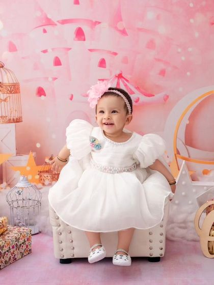 In a magical pink castle setting, this little girl celebrates turning one, looking like a true princess in her white dress.