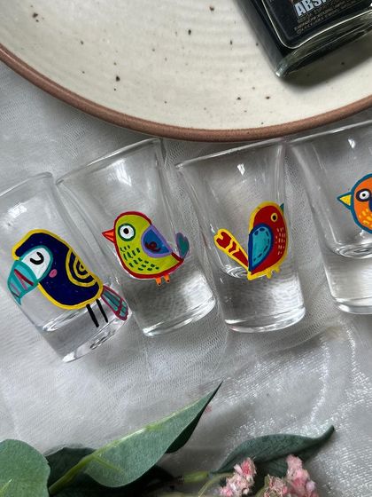 Our hand painted bird shot glasses lined up and ready for a party. This set includes a toucan and other tropical bird designs.