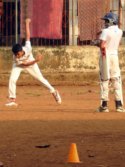 A young bowler in full flow during a practice session on the dirt pitch. This is where raw talent is shaped into skill.