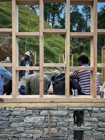 A moment of rest for the construction crew, framed by a newly installed window structure. The work is physically demanding, and the skill of these craftsmen is what brings the architectural vision to life.