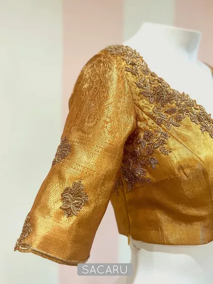 A blouse dipped in gold. This piece is crafted from shimmering gold tissue fabric with tonal embroidery along the neckline and sleeves for a regal look.