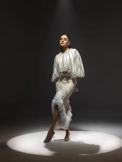 This is another perspective of the spotlighted couture look for Kavita Arora. The pose is slightly different, offering a clearer view of the intricate beadwork and the elegant fall of the feather-detailed skirt, showcasing a modern take on bridal glamour.