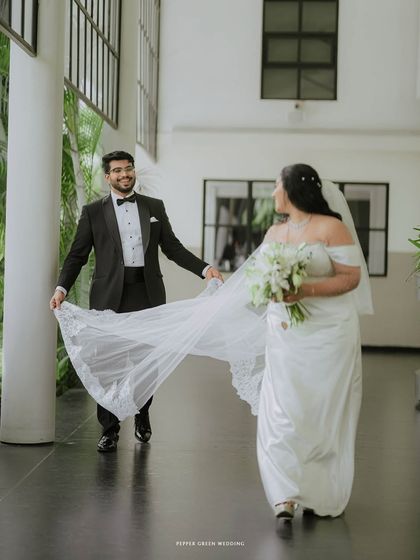 A playful and chivalrous moment as the groom holds his bride's veil. It’s these unscripted interactions that add personality and charm to a wedding album.