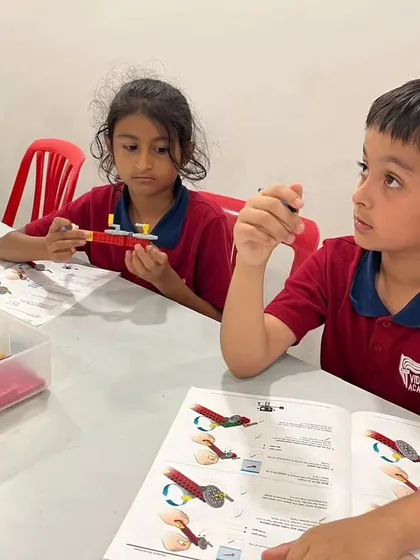 Two students from Vidyashilp Academy work together, following instructions to build a model. Our programs encourage peer learning and teamwork.