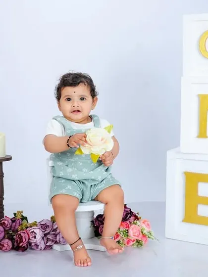 This portrait showcases a clean and classic first birthday theme. The simple white background, gold-lettered 'ONE' blocks, and minimal props put all the focus on the baby's adorable personality.