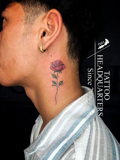 A single red rose tattooed on the neck, a classic symbol of love and beauty.