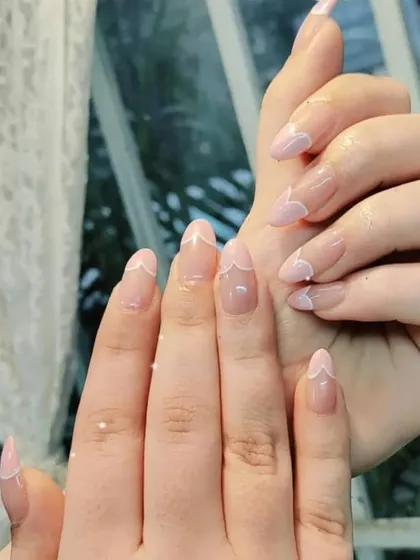 A delicate and feminine take on the French manicure, featuring a soft pink base and fine white lines creating a heart shape at the tip.