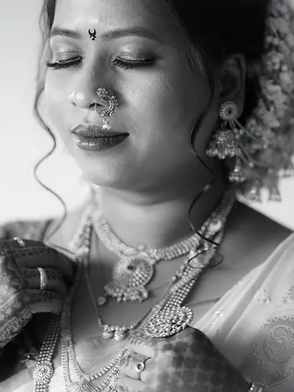 A classic monochrome portrait of a bride. The black and white tones emphasize the rich textures of her jewelry and the serene emotion on her face.
