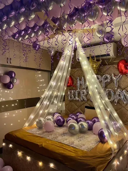 A full view of the purple and silver themed birthday room, showing the bed canopy and balloons on the floor.