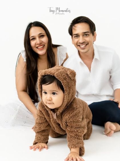 A beautiful family portrait with their little teddy bear. The clean, simple setup allows their happy expressions to be the main focus.