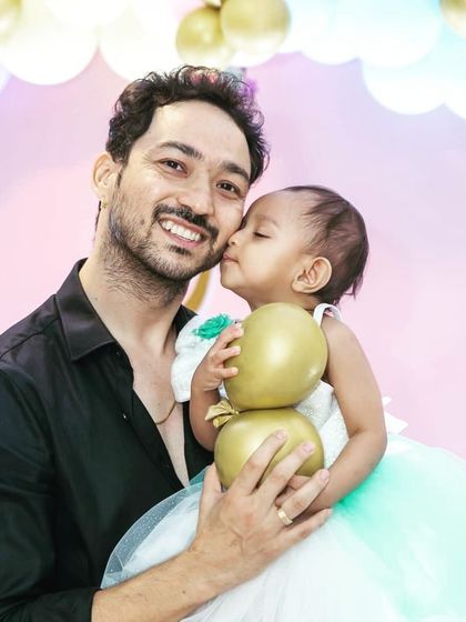 A heartwarming photo of a father and his baby girl sharing a sweet kiss during her birthday celebration.