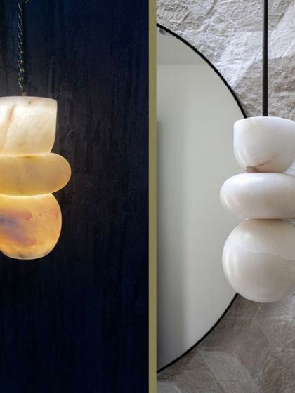 A pendant light made from stacked, pebble-like pieces of marble. This design shows the fixture both off and on, highlighting its sculptural quality.