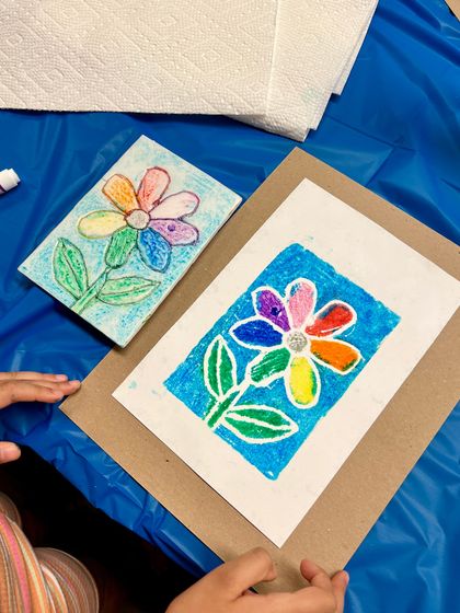 A colorful rainbow flower print created by a young artist. Our workshops are designed to be fun and allow for personal expression.