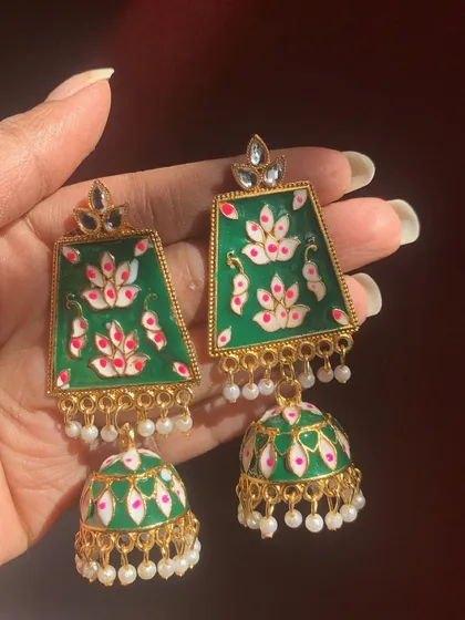 A closer look at the green Meenakari jhumkas with a hand-painted lotus design. The combination of green, white, and pink is simply stunning.