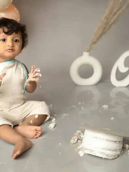 The aftermath of a fun celebration. With frosting on his hands and a toppled cake, this little one has clearly had a wonderful time at his first birthday shoot.