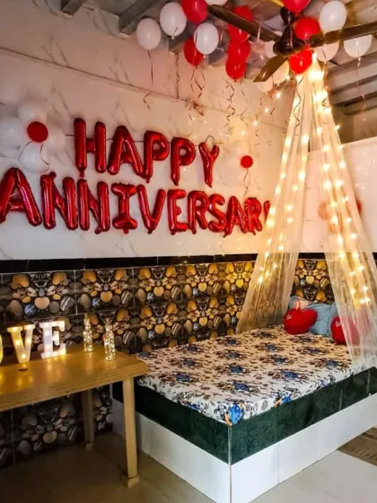 This is a cozy and charming anniversary room decoration I did for a client. The setup features a simple canopy draped with fairy lights over the bed, 'Happy Anniversary' foil balloons on the wall, and illuminated 'LOVE' letters for a warm, personal touch.