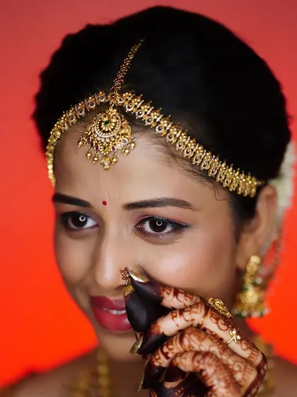 A playful and shy pose from the bride, highlighting her intricate henna and nose ring.